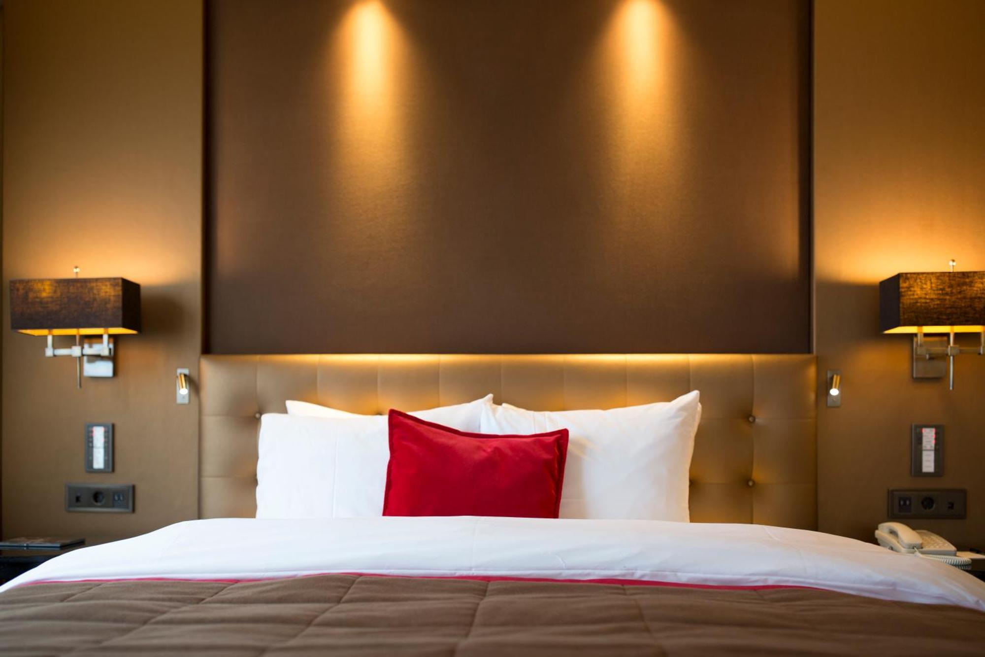 Grand Hotel Huis Ter Duin ノールトウェイク 部屋 写真 A bed with a red pillow